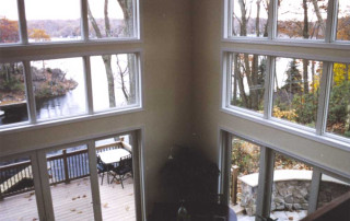 View from interior balcony overlooking the Living room. Main deck, curved patio and lake seen through the windows.