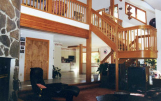 The cathedral ceilinged, sunken Living room with the curved stair landing and a glimpse of the lake beyond.