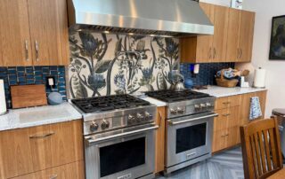 Double ovens with tile mural backsplash